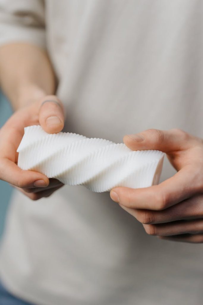 Detailed view of hands grasping a modern spiral-shaped plastic piece.