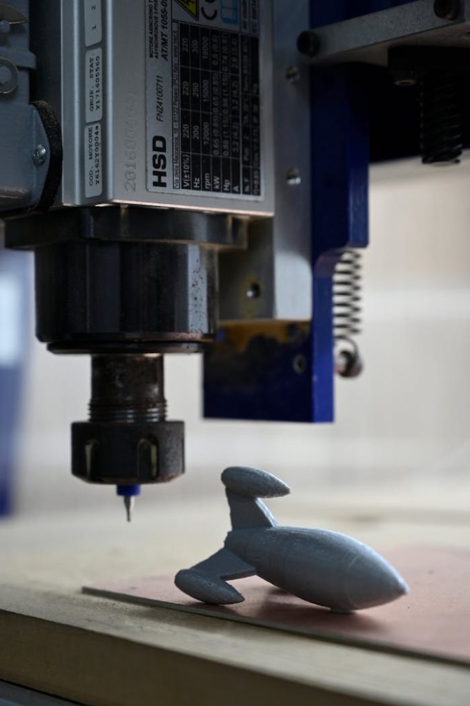 Close-up of a modern milling machine producing a 3D model rocket, highlighting technology and precision.