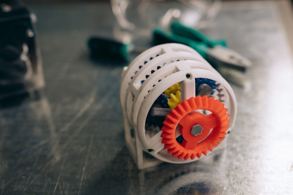 A close-up photo of a 3D printed gear mechanism on a metallic workbench, highlighting innovation and technology.